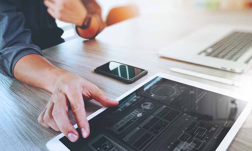 Man working at desk with tablet, smartphone and laptop